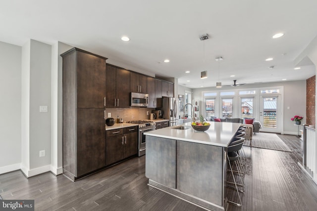 kitchen featuring a sink, dark brown cabinetry, appliances with stainless steel finishes, and an island with sink