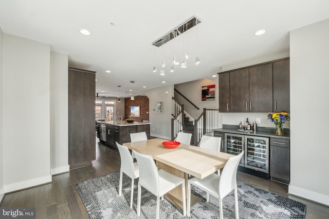 dining room featuring dark wood-style floors, stairway, beverage cooler, and a bar