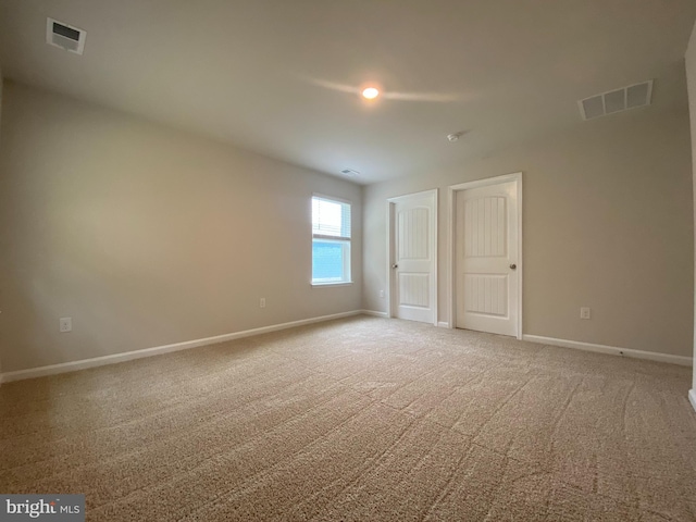 carpeted empty room featuring visible vents and baseboards