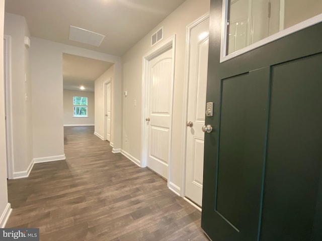 hall with dark wood finished floors, visible vents, and baseboards