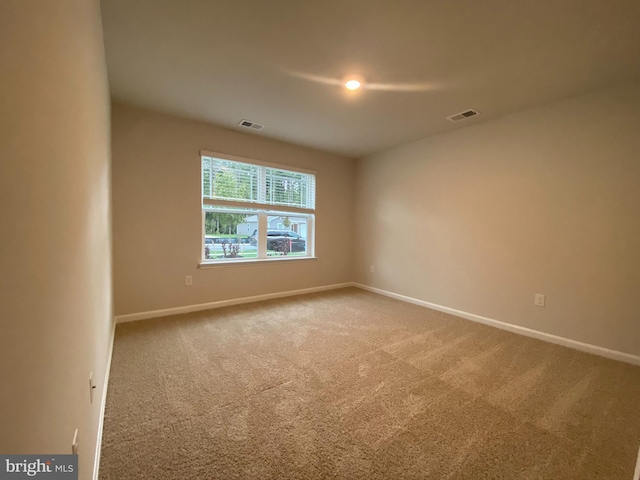 carpeted empty room with visible vents and baseboards