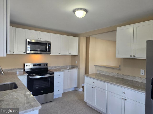 kitchen featuring a sink, white cabinets, light stone counters, and stainless steel appliances