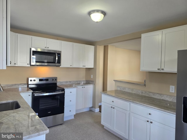 kitchen featuring light stone countertops, white cabinetry, stainless steel appliances, and a sink