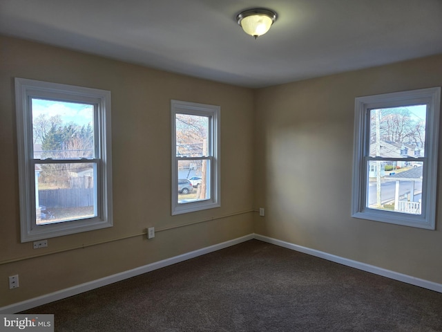 unfurnished room with dark colored carpet and baseboards