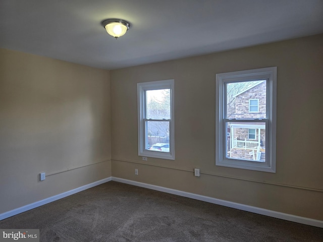 unfurnished room with baseboards and dark colored carpet