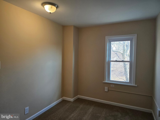 empty room featuring baseboards and dark carpet