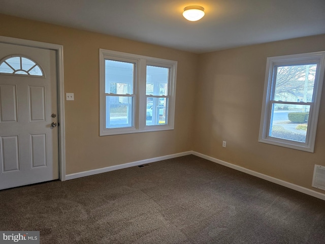 entrance foyer featuring visible vents, baseboards, and dark carpet