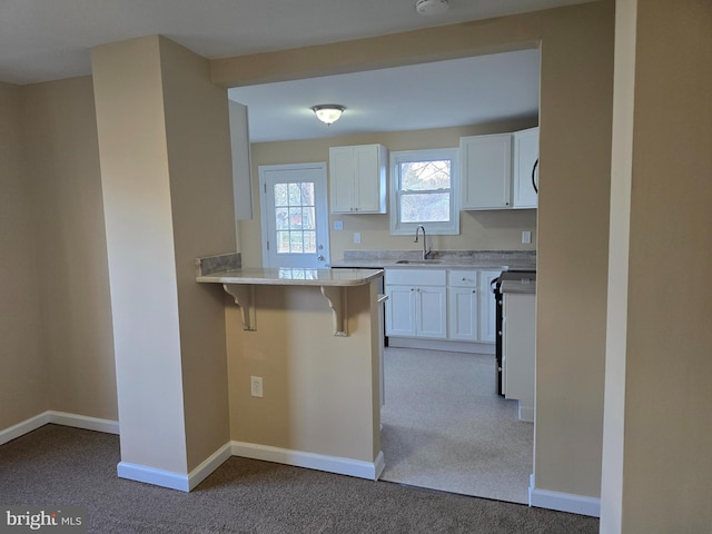 kitchen featuring white cabinetry, stove, a kitchen breakfast bar, and a sink