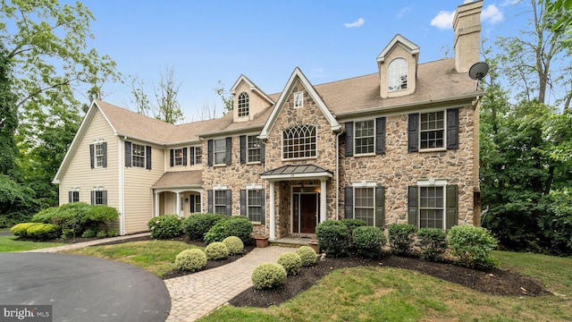 colonial house with stone siding and a chimney