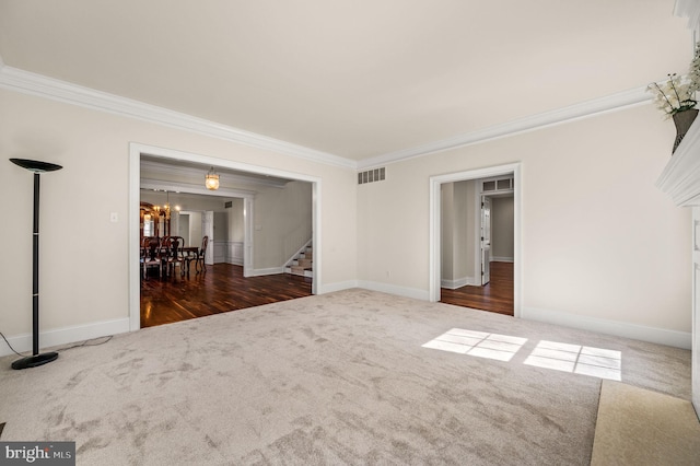 empty room featuring visible vents, carpet, a chandelier, stairway, and ornamental molding