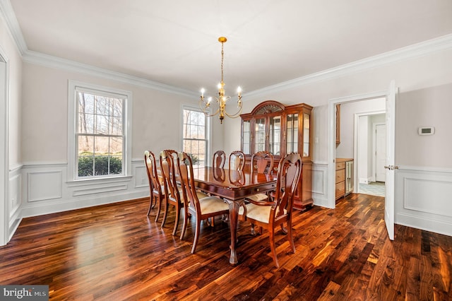 dining space featuring an inviting chandelier, ornamental molding, dark wood-style flooring, and a decorative wall