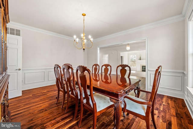 dining area featuring visible vents, a fireplace, dark wood-style flooring, crown molding, and a notable chandelier