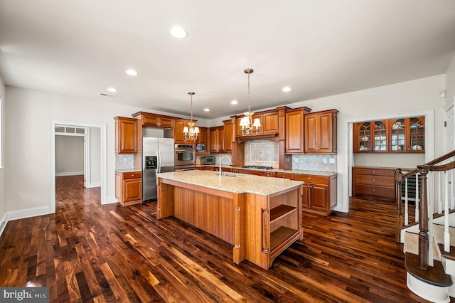 kitchen with dark wood-style floors, a center island with sink, open shelves, stainless steel appliances, and brown cabinets