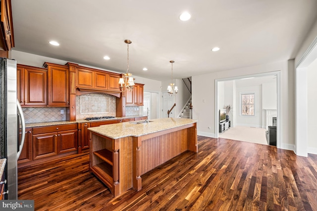 kitchen with tasteful backsplash, a fireplace, freestanding refrigerator, and a kitchen island with sink