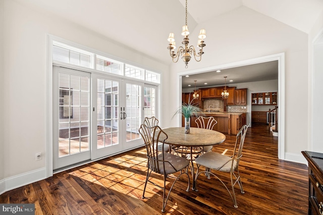 dining room featuring french doors, lofted ceiling, an inviting chandelier, and dark wood-style floors