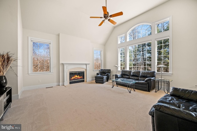 carpeted living area featuring a fireplace with flush hearth, high vaulted ceiling, baseboards, and a ceiling fan