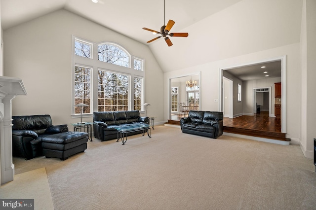 carpeted living area featuring recessed lighting, ceiling fan with notable chandelier, high vaulted ceiling, and baseboards