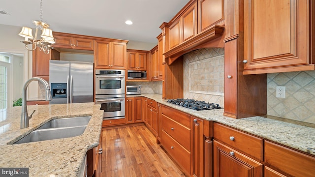 kitchen with a sink, stainless steel appliances, brown cabinets, and light wood-style flooring