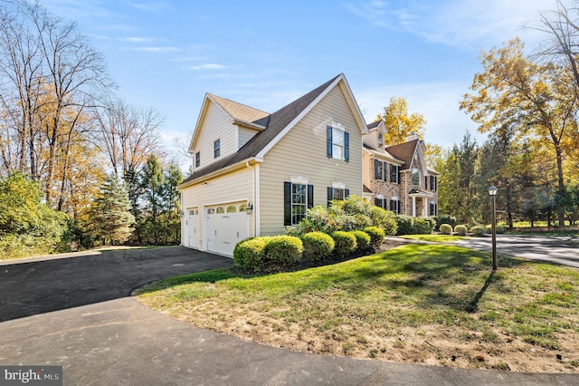 view of side of home with an attached garage, a lawn, and driveway