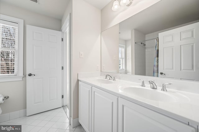 bathroom with tile patterned floors, double vanity, baseboards, and a sink