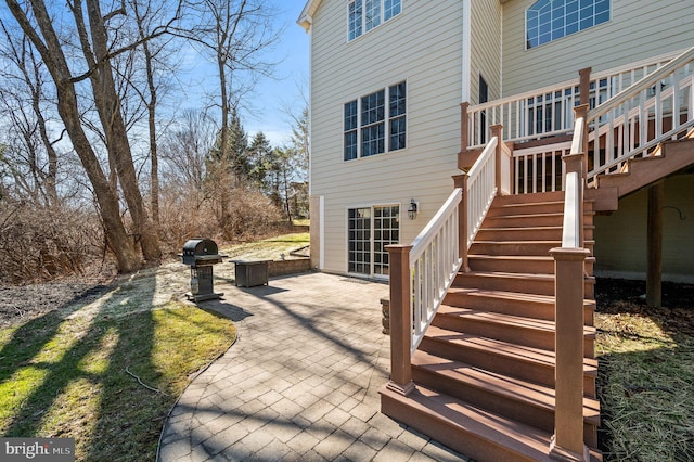 deck with area for grilling, stairway, and a patio area