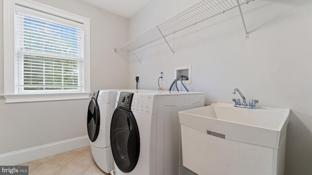 clothes washing area featuring baseboards, laundry area, separate washer and dryer, light tile patterned flooring, and a sink