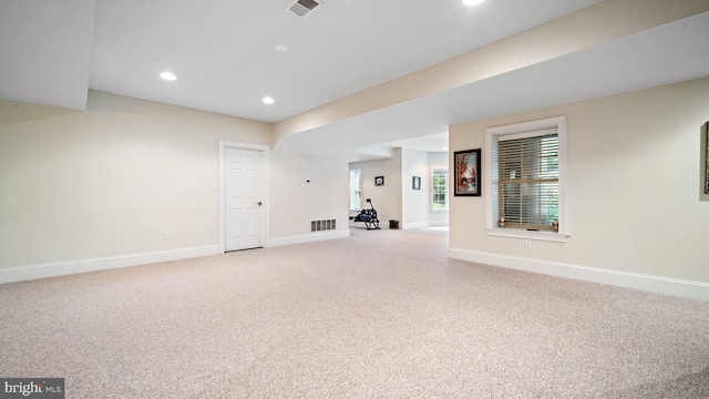 interior space featuring light colored carpet, visible vents, and baseboards