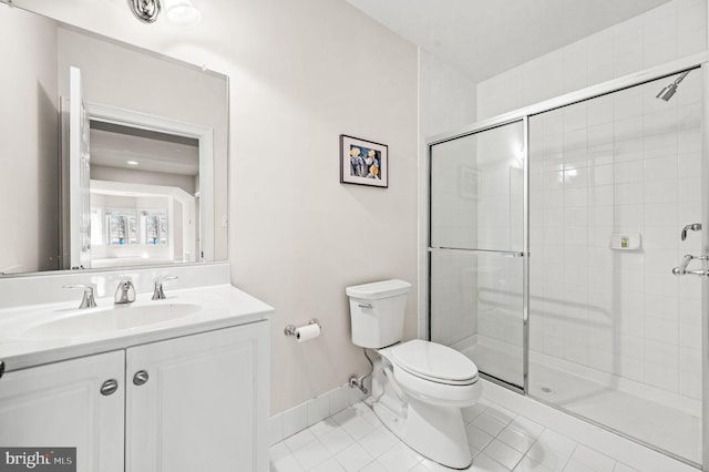 full bath featuring toilet, a stall shower, tile patterned flooring, baseboards, and vanity