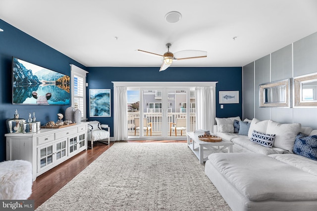 living room featuring a wealth of natural light, ceiling fan, and dark wood-style flooring