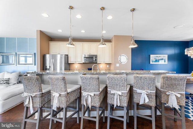 kitchen featuring recessed lighting, stainless steel appliances, a kitchen breakfast bar, and light stone countertops