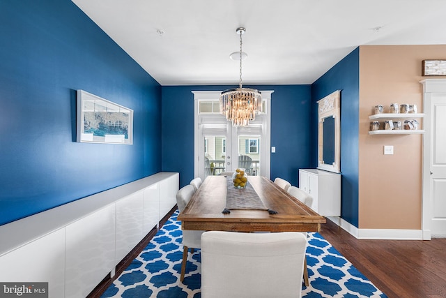 dining space featuring a chandelier, baseboards, and wood finished floors