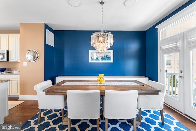 dining area featuring dark wood-type flooring, a notable chandelier, visible vents, and baseboards