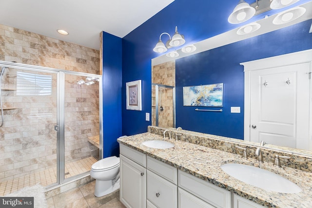 bathroom with double vanity, toilet, a stall shower, and a sink