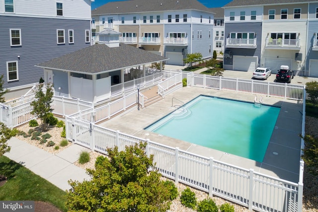 pool with a residential view, a patio, and fence