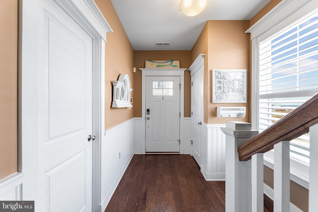 entryway with a wainscoted wall, dark wood-type flooring, and visible vents