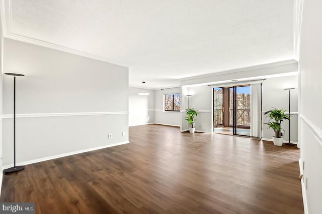 unfurnished living room featuring crown molding, plenty of natural light, wood finished floors, and baseboards