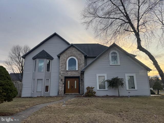 view of front of home featuring a yard and brick siding