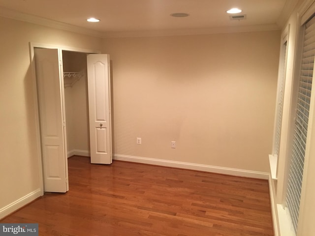 unfurnished bedroom with crown molding, wood finished floors, baseboards, and visible vents