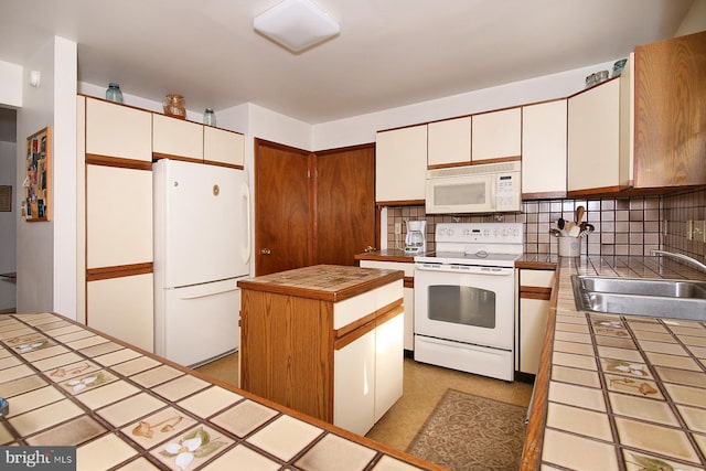 kitchen with white appliances, a sink, tile counters, backsplash, and a center island