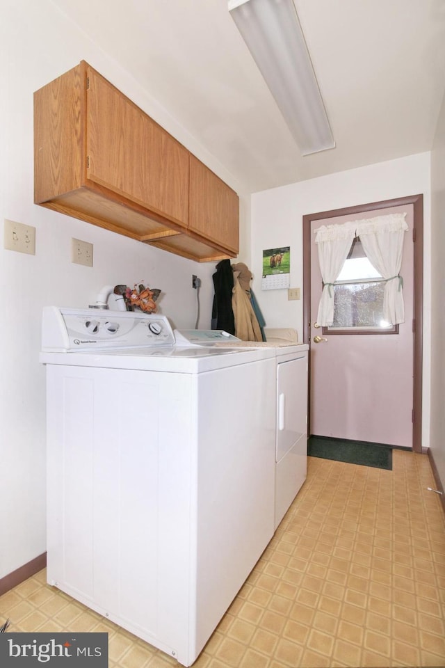 laundry room with washing machine and dryer, cabinet space, and light floors