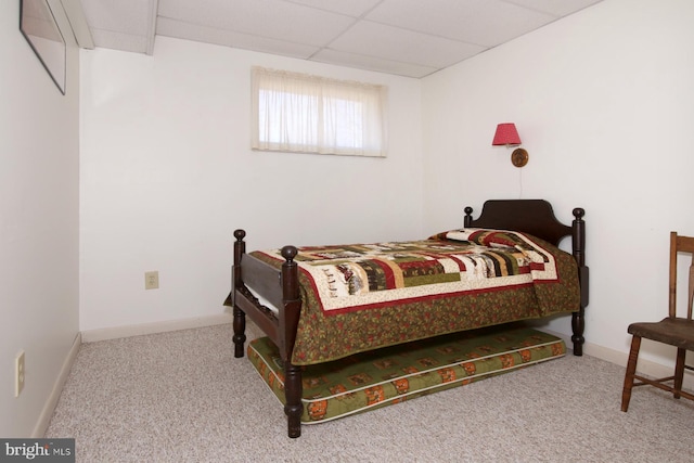 carpeted bedroom featuring a paneled ceiling and baseboards