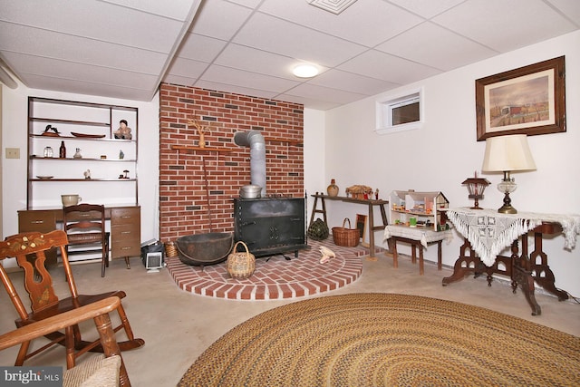 sitting room featuring a drop ceiling and a wood stove