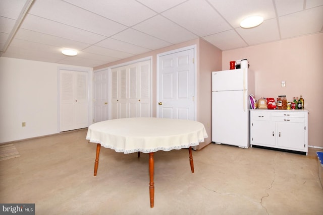 dining space with a drop ceiling and concrete floors