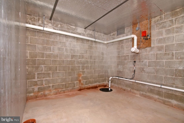 bathroom featuring unfinished concrete floors and concrete block wall