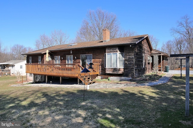 rear view of house with a wooden deck, a lawn, and a chimney