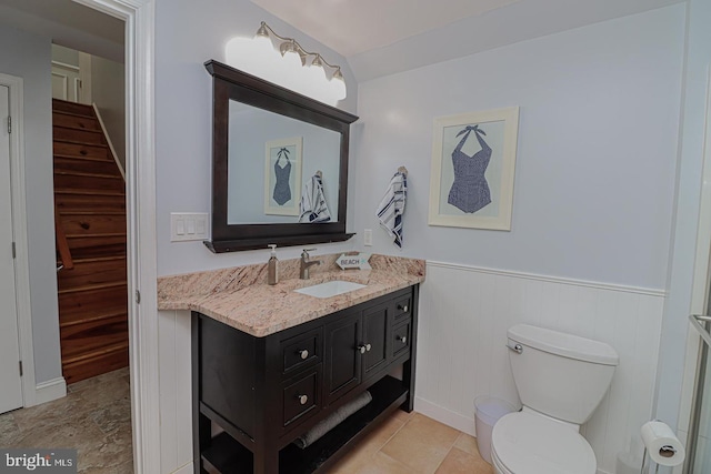 bathroom with toilet, a wainscoted wall, and vanity