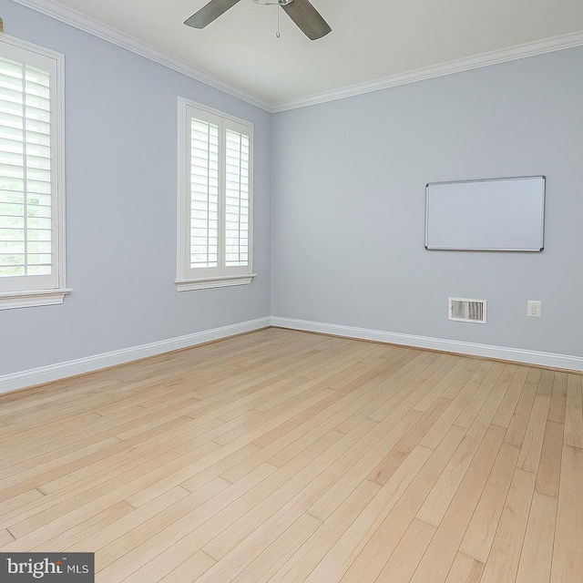 empty room featuring a ceiling fan, visible vents, wood finished floors, baseboards, and ornamental molding