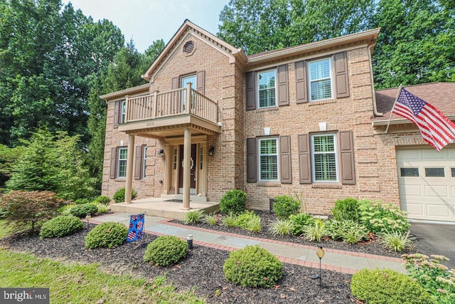 view of front of property featuring a garage, brick siding, and a balcony