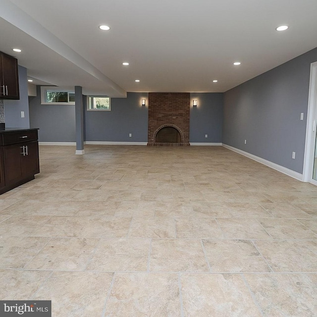unfurnished living room with recessed lighting, baseboards, and a brick fireplace