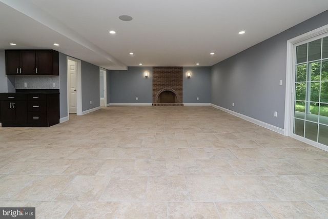 unfurnished living room featuring baseboards, a brick fireplace, and recessed lighting